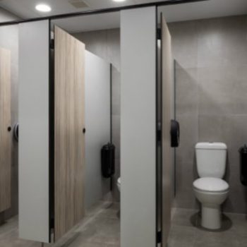 Restroom cubicles featuring black Pod Petite manual units installed in side wall