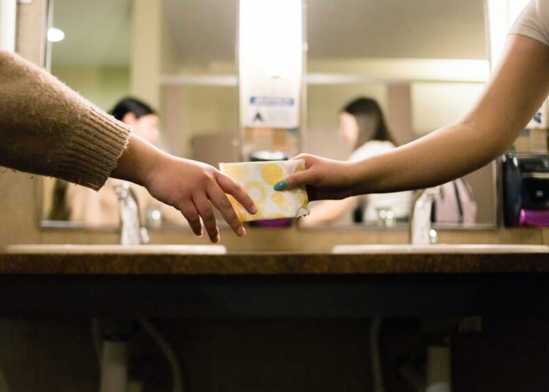 Women passing sanitary pad in washroom